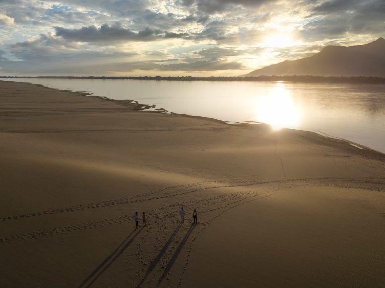 Low sunlight falls across the sandbank and the Mekong.