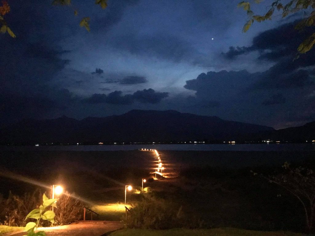Small lights trace the sandy riverbank after dark.