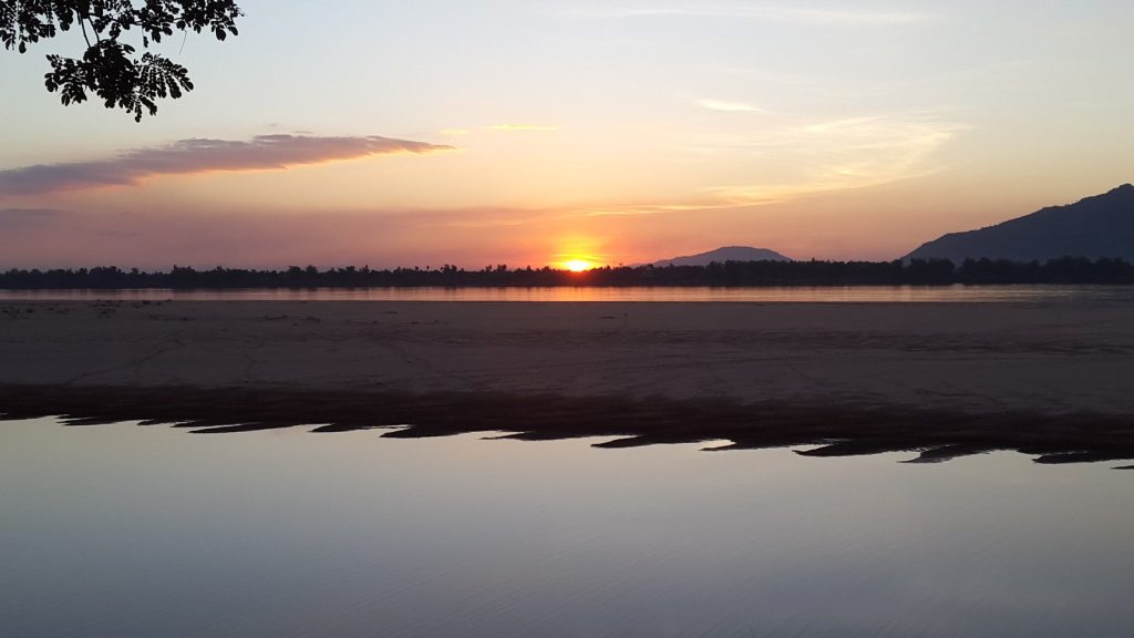 The low sun draws a bright reflection across the Mekong.