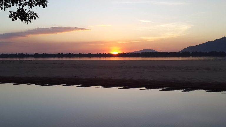 The low sun draws a bright reflection across the Mekong.